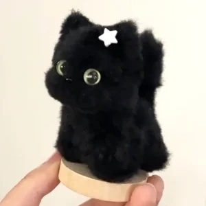 A small, handmade cat plush toy named Meowgic, crafted from soft chenille stem with glass eyes. Each one is unique and designed to offer calm and companionship.