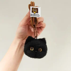 A small, cat-shaped, handmade plush charm with a soft, fluffy texture and shiny glass eyes, attached to a loop and clip. Each charm is unique and comes in various colors.