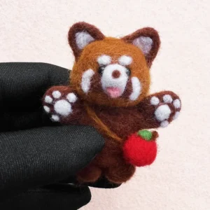 Handmade wool felt red panda plush holding a tiny apple, crafted with detailed needle felting.